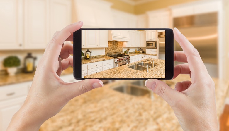 Hand photographing house apartment kitchen island room for sale or rent with phone smartphone closeup point of view in modern luxury condo home tour with blurry bokeh background